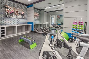 A spinning bike is in the foreground of a brightly lit gym